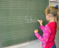 Bild vergrößern: Mädchen schreibt an Tafel